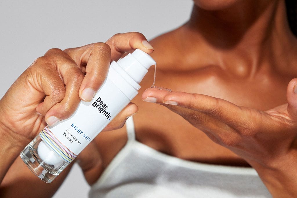 Person dispensing skincare product from a white bottle onto their hand.